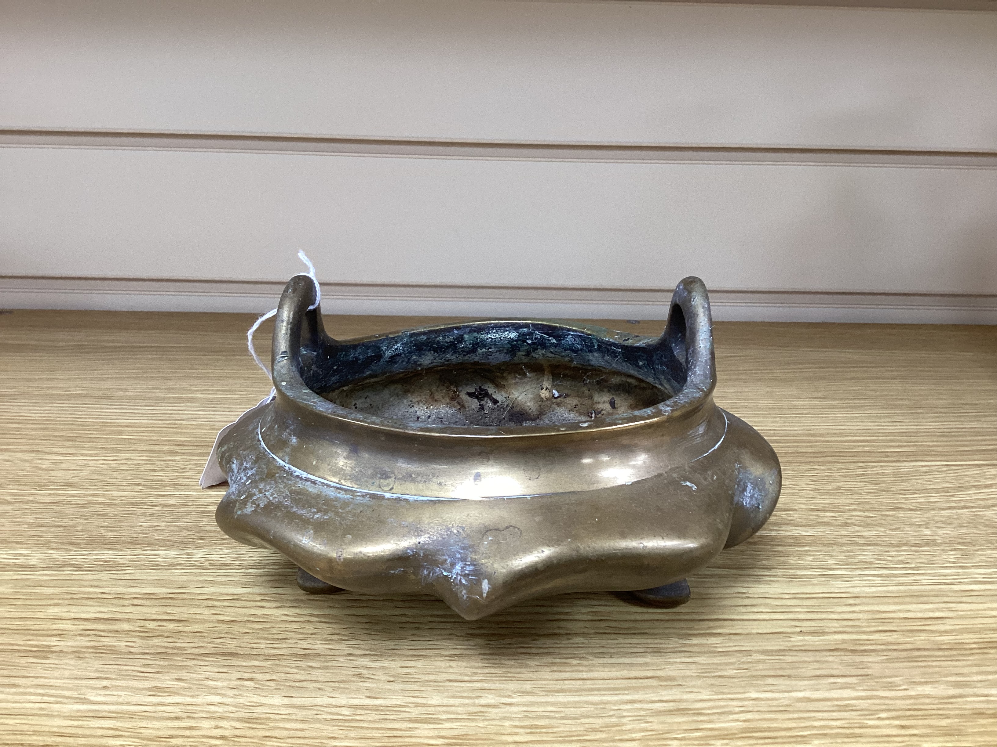 A Chinese bronze tripod censer with twin handles on hardwood stand, censer 19cm wide